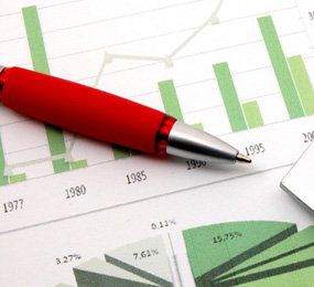 A red pen laying on a vague bar chart and pie graph, neither showing any data other than years and percentages.